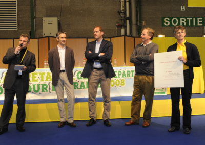 Christophe Penot, l’organisateur, salue les confrères présents en salle de presse ce vendredi 4 juillet 2008, à Brest, sur le site du Grand Départ du Tour de France. À ses côtés, outre Jean-Julien Ezvan et Patrice Clerc, on reconnaît Christian Prudhomme, successeur de Jean-Marie Leblanc à la tête du Tour de France, et Sophie Moressée-Pichot, responsable des opérations de sponsoring de LCL sur ce Tour.