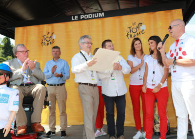 Éric Marchyllie au micro. Responsable sponsoring de Carrefour France, il veut à la fois saluer un ami et un reporter qui restera dans la mémoire du Prix Jacques-Goddet.