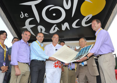 Éric Marchyllie, responsable sponsoring de Carrefour France, a remis à Jean-François Quénet le portfolio du 7e Prix Jacques-Goddet en compagnie de Michel Rocard et de Christian Prudhomme. Bernard Hinault, le quintuple vainqueur du Tour de France, à gauche, leur a fait l’amitié de leur prêter main forte !