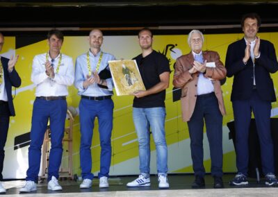 Temps de pause et applaudissements mérités. Thomas Perotto reçoit l’hommage de Xavier Jan, président de la Ligue Nationale de Cyclisme, de Julien Goupil, directeur médias & partenariats d’Amaury Sport Organisation, de Jean-Étienne Amaury, de Jean-Claude Trichet et de Laurent-Éric Le Lay, directeur des sports de France Télévision.